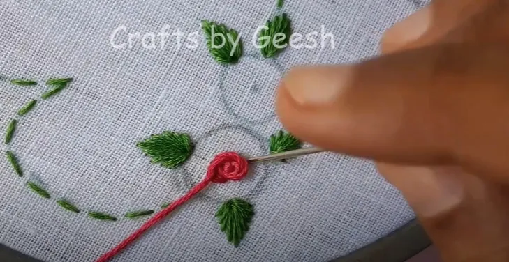 Detail of a rose flower being embroidered using the stem stitch technique to create a textured floral design.