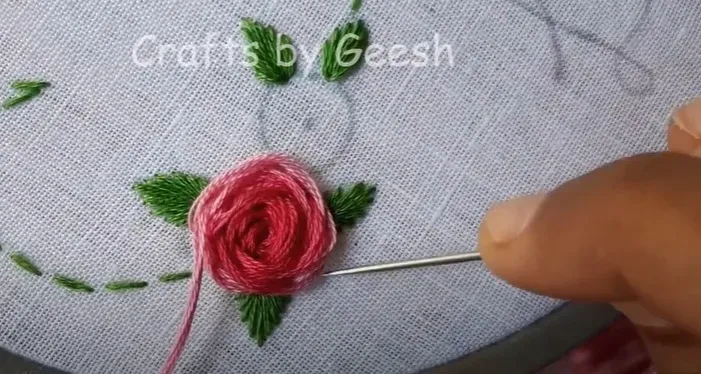 Detail of a rose flower being embroidered using the stem stitch technique to create a textured floral design.
