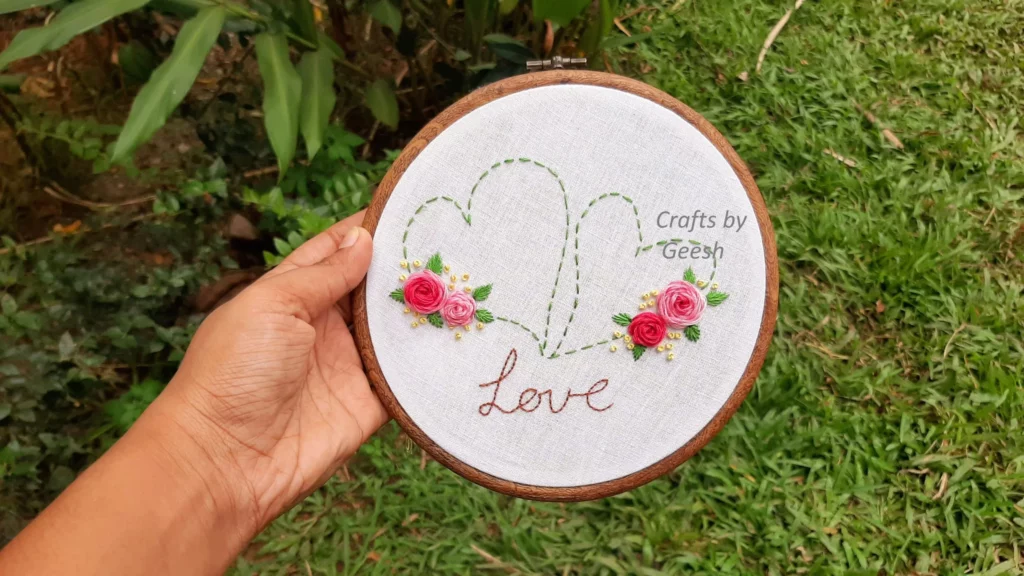 Finished Love Heart hand embroidery hoop art featuring red stem stitch roses and green satin stitch leaves for Valentine's Day.